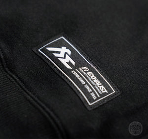 Fi EXHAUST authenticity patch on a black hoodie's lower hip.